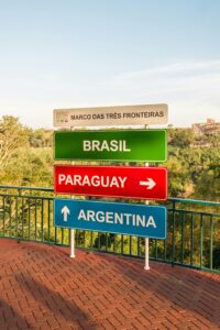 Colorful directional signs marking the Triple Frontier between Brazil, Argentina, and Paraguay.
