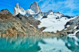 Spectacular view of lake with turquoise water in highland with rough rocks covered with snow