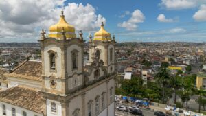 Aerial view of a historic church with golden domes in Salvador, Brazil, overlooking a vibrant urban landscape.